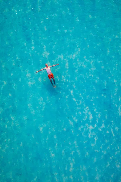 熱帯の海の水に浮かんでいる男のドローンビュー。空中風景 — ストック写真