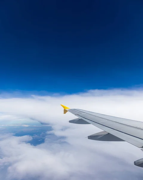 Uitzicht op de vleugel van een vliegtuig vliegen boven de wolken op hoge — Stockfoto