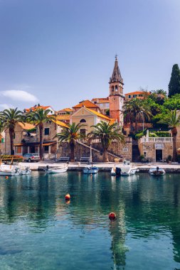 Mavi gökyüzünde güneşli: Splitska karşı kilise bina ve palmiye ağacı