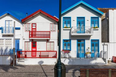 Kosta Nova, Aveiro, Portekiz 'de renkli evleri olan bir cadde. Çizgili evleri olan cadde, Costa Nova, Aveiro, Portekiz. Kosta Nova, Aveiro, Portekiz 'deki renkli evlerin cepheleri.
