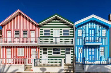 Kosta Nova, Aveiro, Portekiz 'de renkli evleri olan bir cadde. Çizgili evleri olan cadde, Costa Nova, Aveiro, Portekiz. Kosta Nova, Aveiro, Portekiz 'deki renkli evlerin cepheleri.