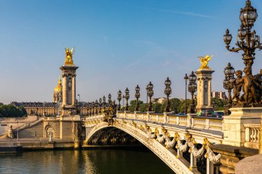 Pont Alexandre III köprüsü, güneşli bir yaz sabahı Seine nehrinin üzerinde. Art Nouveau lambaları ve heykellerle süslenmiş bir köprü. Paris, Fransa 'daki Seine Nehri' nin karşısındaki Alexander III Köprüsü..