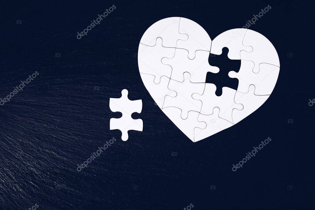 Heart-shaped jigsaw puzzle on color background. Puzzle heart on wooden background. A missing piece of the heart puzzle. Heart shape jigsaw puzzle. Puzzles in the shape of a heart. 