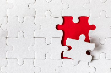 Beyaz yapboz. Renkli arka planda beyaz yapboz parçaları. Renk arkaplanındaki tamamlanmamış beyaz yapboz parçaları. 