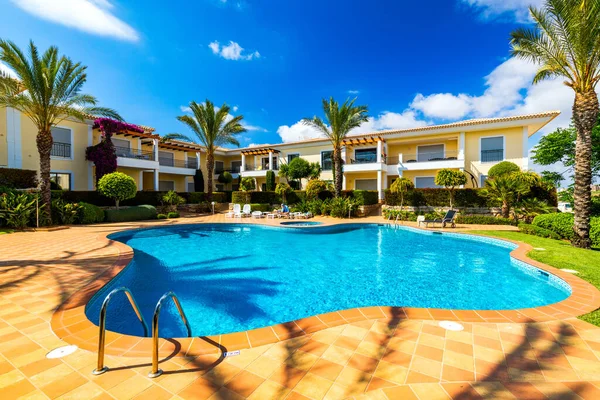 Great backyard with swimming pool, hot tub and lounge chairs. Swimming pool in backyard. Incredible swimming pool and garden with palm trees and flowers in a sunny day.
