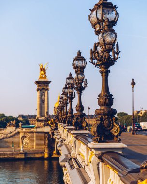 Pont Alexandre III köprüsü, güneşli bir yaz sabahı Seine nehrinin üzerinde. Art Nouveau lambaları ve heykellerle süslenmiş bir köprü. Paris, Fransa 'daki Seine Nehri' nin karşısındaki Alexander III Köprüsü..