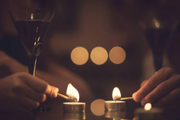 Romantic atmosphere. Candles, glasses of red wine and two hands.