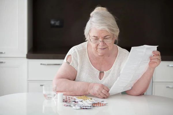 Gri saçlı adam ve onun ilaçlar bir sürü. Büyükanne uygulama tablet eğitimi okur