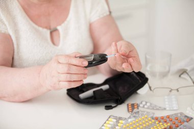 Ev laboratuvar. Büyükanne kan şekeri düzeyini denetler. Hapları