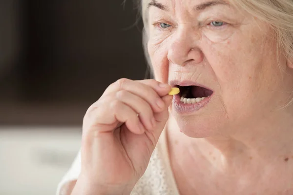 祖母吃了一颗黄色的药丸 退休妇女 — 图库照片