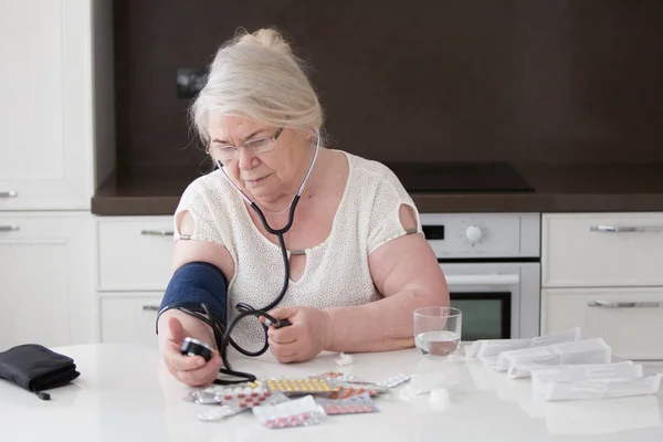 Büyükanne gözlük ile tonometer basınç ölçer.