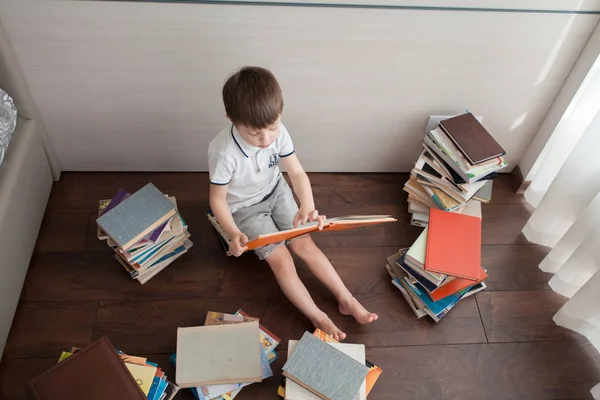 Sitzt Der Junge Auf Büchern Und Liest Ihn Herum Liegen — Stockfoto