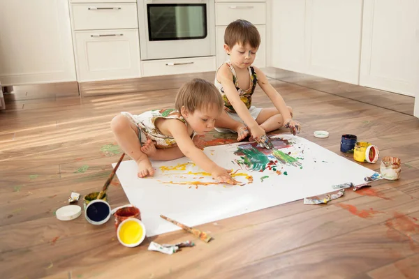 Bir büyük beyaz kağıdın üzerine boya ile iki kardeş boya.
