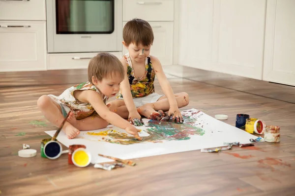 Bir büyük beyaz kağıdın üzerine boya ile iki kardeş boya.