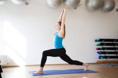 Güzel atletik sarışın kız bir spor mat spor egzersizleri yapıyor.