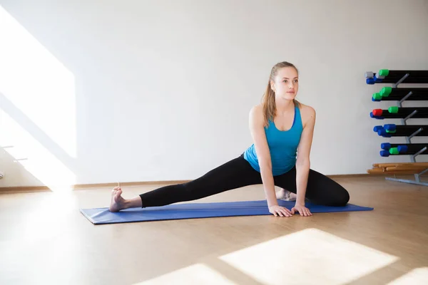 Güzel atletik sarışın kız bir spor mat spor egzersizleri yapıyor.