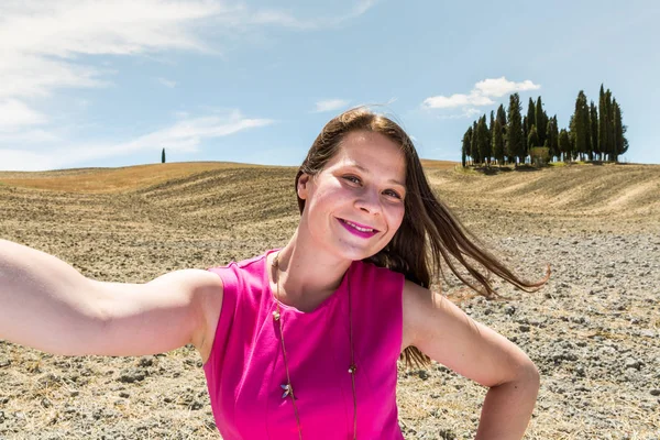 Девушка, стоящая на полях Тосканы летом в пурпурном платье — стоковое фото