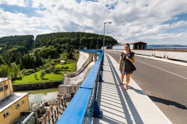 Girl at the concrete dam and hydroelectric plant station in Orava clipart