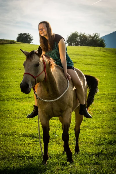 Meisje in een groene jurk zittend op een bruin paard in Slowakije — Stockfoto