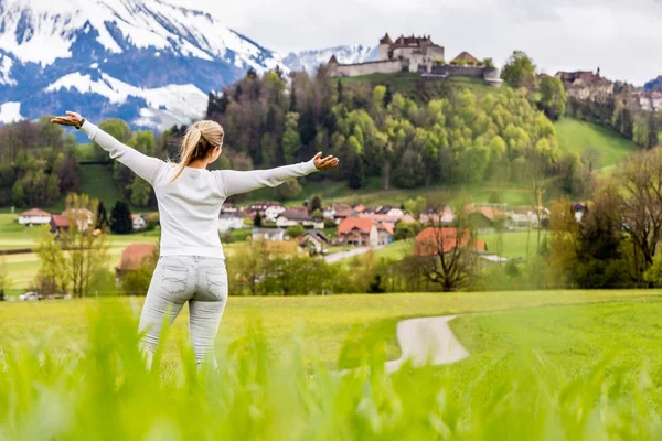 Flicka på en äng framför den Grueyeres byn i Schweiz — Stockfoto