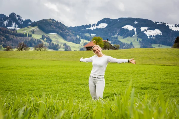 Niña en un prado frente a la aldea de Gruyeres en Suiza — Foto de Stock