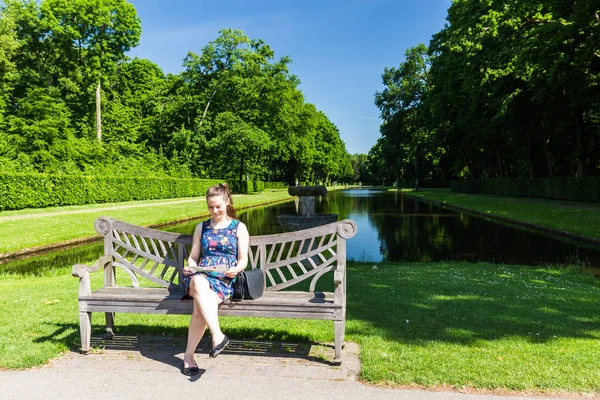 Lány ül a padon, és nézte a térképet, a park a De Haar Castle, Hollandia — Stock Fotó