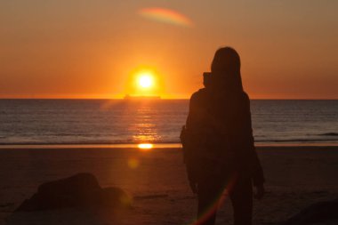 Günbatımında Atlantik Okyanusu kıyısındaki insanlar