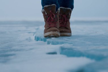 Insulated boots on the ice of lake Baikal clipart