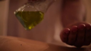 Masaj terapist dökülen yağı vücut üzerinde