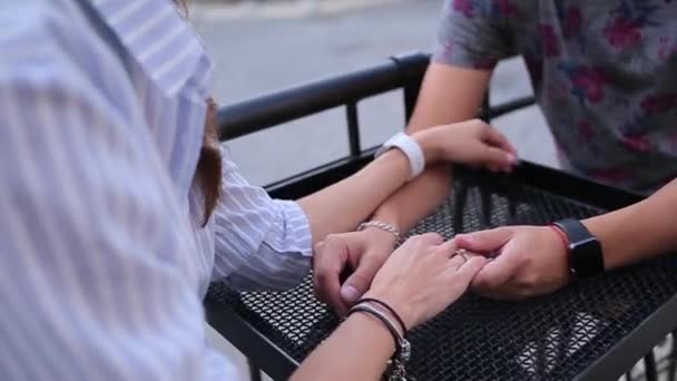 Пара тримає руки сидячи у вуличному кафе — стокове відео