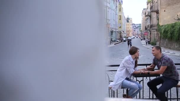 Пара, сидящая на фоне старого города — стоковое видео