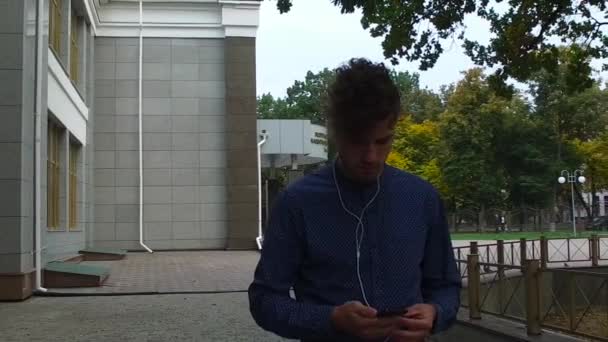 Człowiek słucha muzyki idąc ulicą — Wideo stockowe