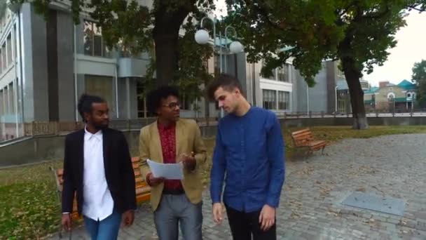 Guys discuss papers walking the autumn street — Stock Video
