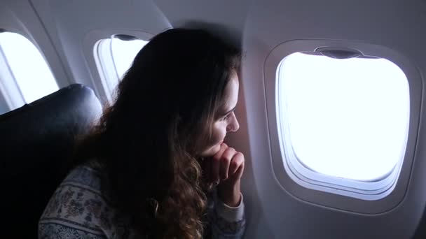 Girl looking out of the window in the plane — Stock Video