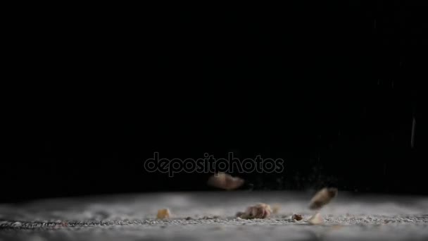 Орехи падают на вращающуюся поверхность черного фона — стоковое видео