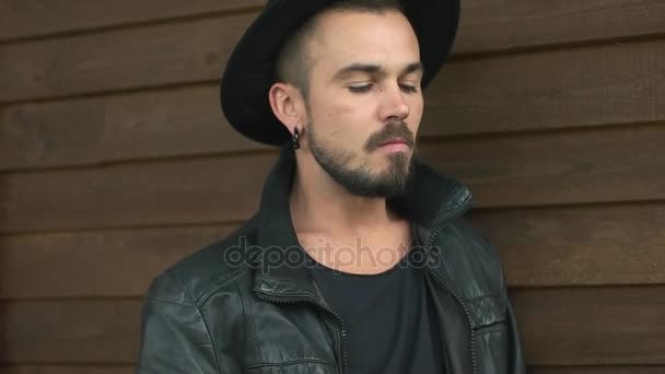 Homme avec une barbe fume près du mur en bois — Video