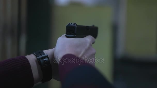 Мужчина держит пистолет в тире — стоковое видео