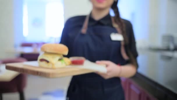 Chica camarera lleva una hamburguesa — Vídeo de stock
