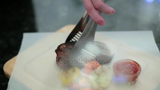 Шеф-повар кладет стейки и овощи — стоковое видео