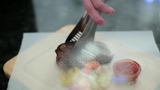 Chef-kok legt steak en groenten — Stockvideo