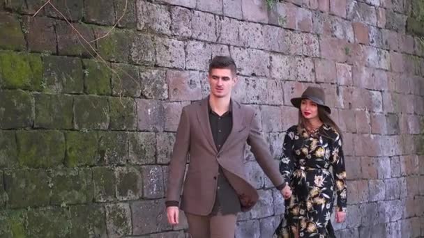 レンガの壁の近く歩いているカップル — ストック動画