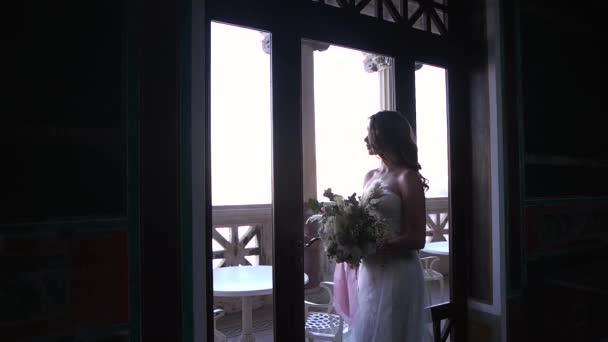 Невеста с цветами у окна — стоковое видео