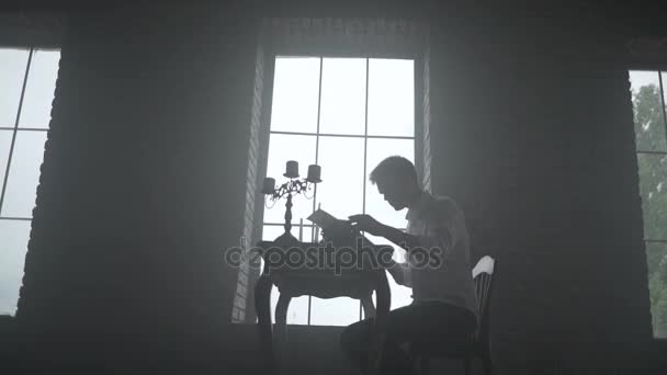 Man att skriva på en skrivmaskin på fönsterbakgrund — Stockvideo