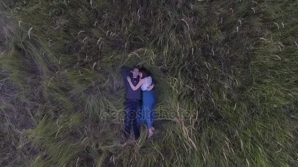 Пара, лежащая в траве в поле — стоковое видео
