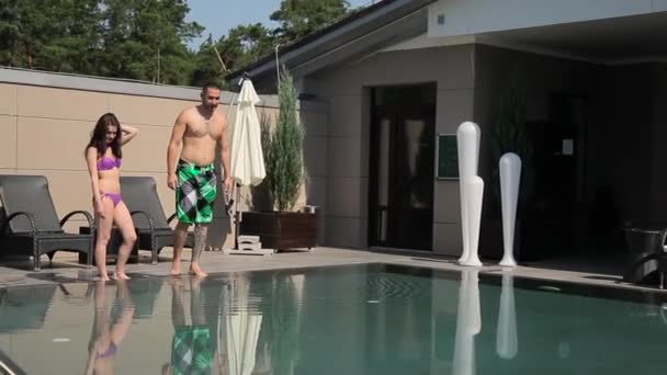 Cara com uma garota pulando na piscina — Vídeo de Stock