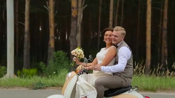 Recién casados montados en un scooter pequeño — Vídeo de stock