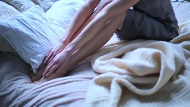 Menina acariciando as pernas na cama — Vídeo de Stock