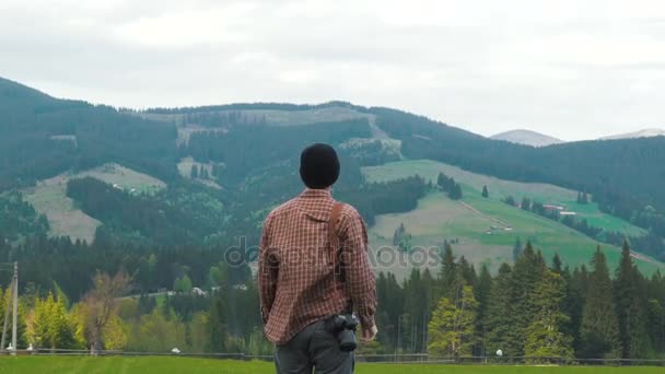 Вдохновленный фотограф поднимает руки в горах — стоковое видео