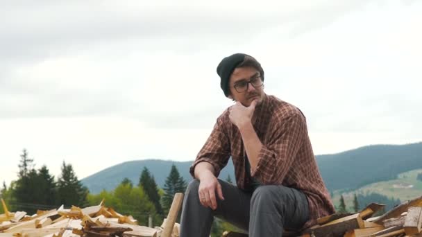 Man is sitting on the heap of firewood — Stock Video