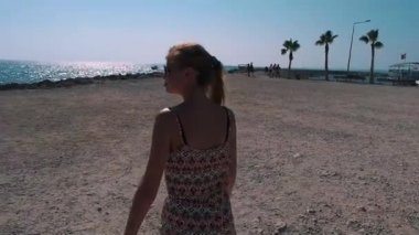 palmiye ağaçları ile kıyı şeridi boyunca bir kız yürüyor